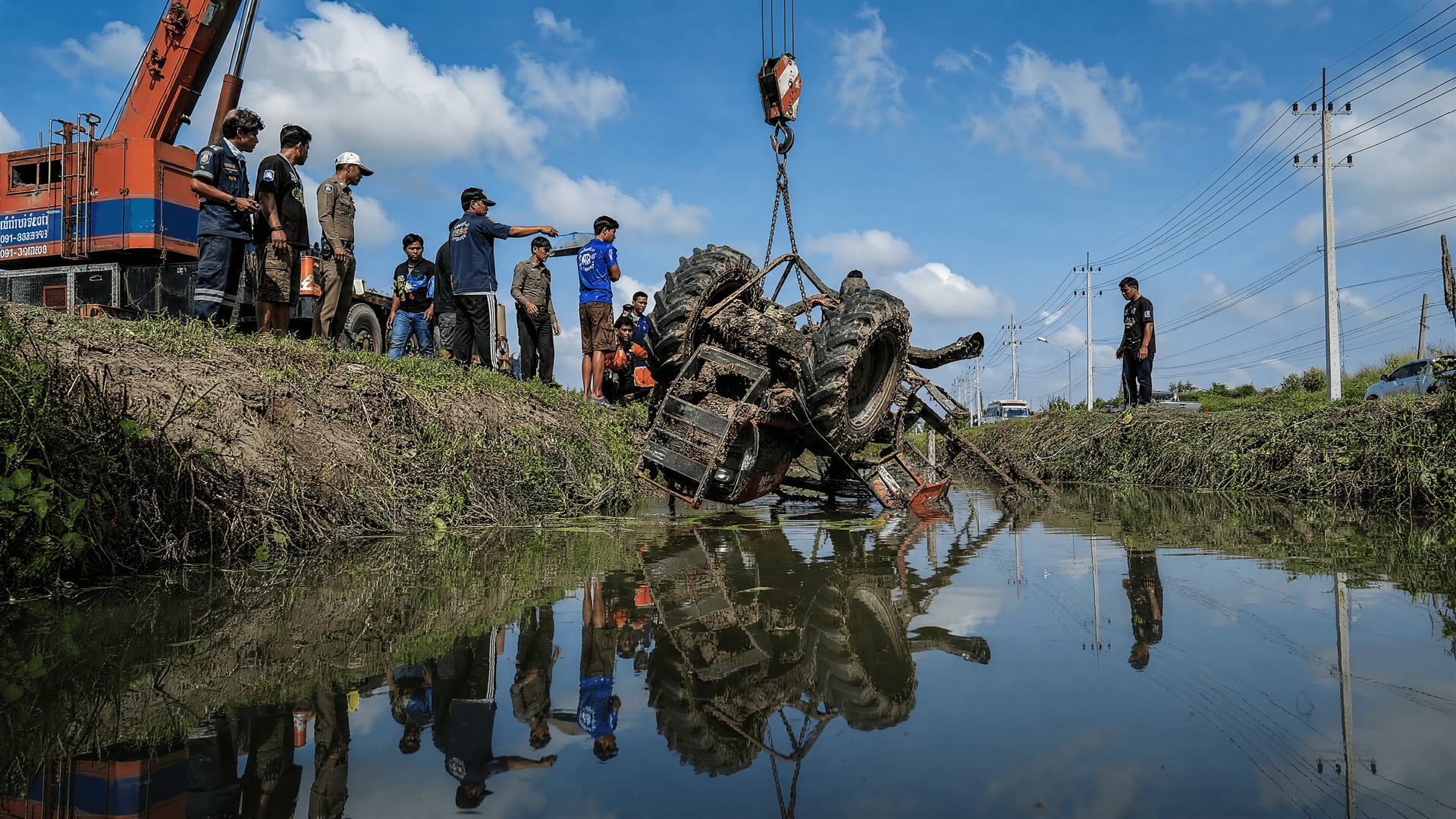 Rescue crane lifting an overturned tractor from an irrigation canal in Bang Ban, Ayutthaya