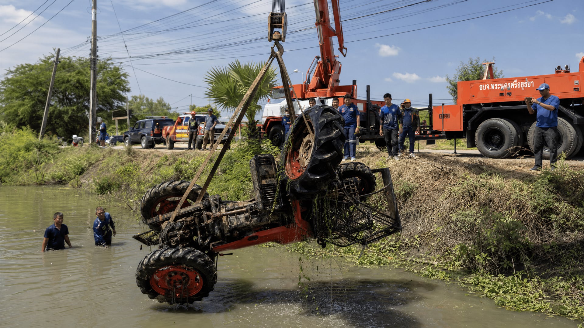 Rescue crane lifting overturned tractor from irrigation canal in Bang Ban, Ayutthaya