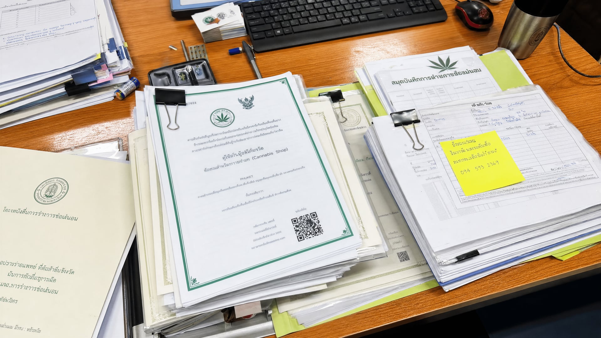 Cannabis shop permits and inspection records arranged on a Phuket district office desk